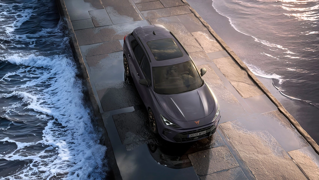 Vue latérale du Cupra Terramar hybride rechargeable sur route de montagne